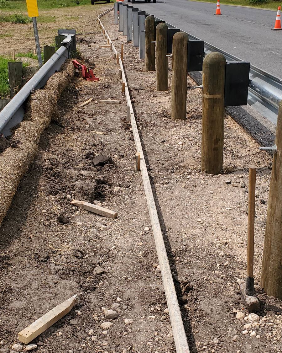 Curb forms set beside roadside guardrail posts