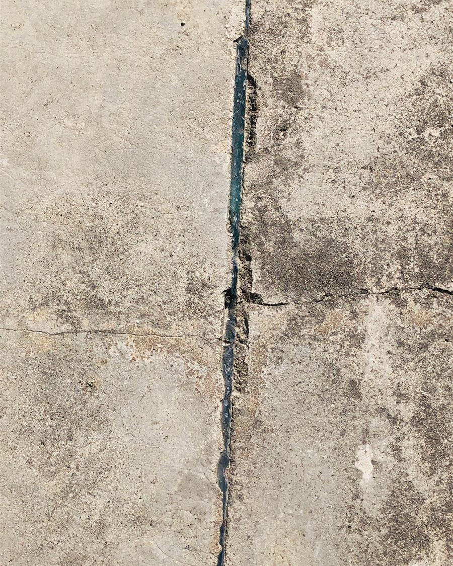 A crack running along a weathered concrete surface