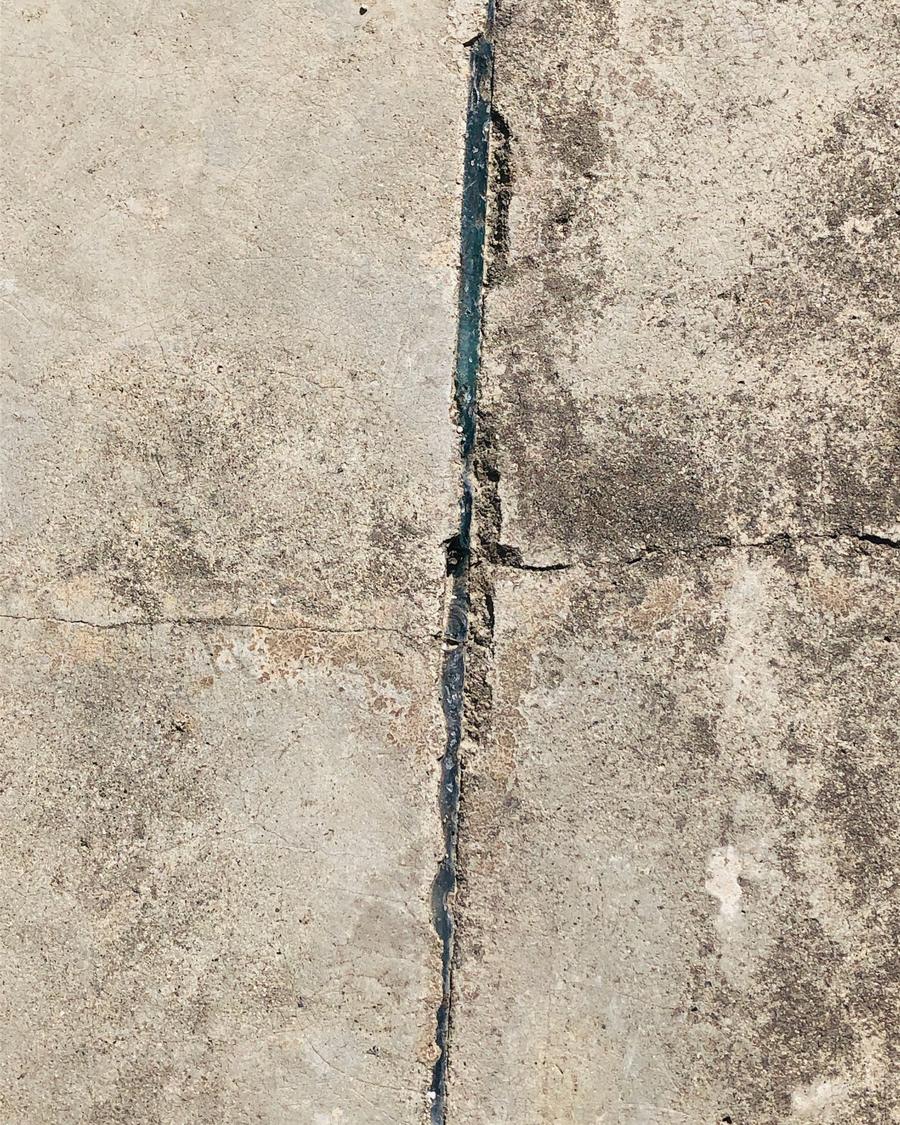 A crack running along a weathered concrete surface