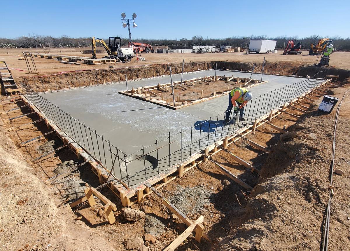 Concrete foundation slab with rebar and formwork being cured at an Ultra Pro job site