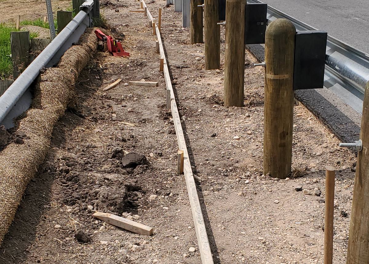 Curb forms set beside roadside guardrail posts